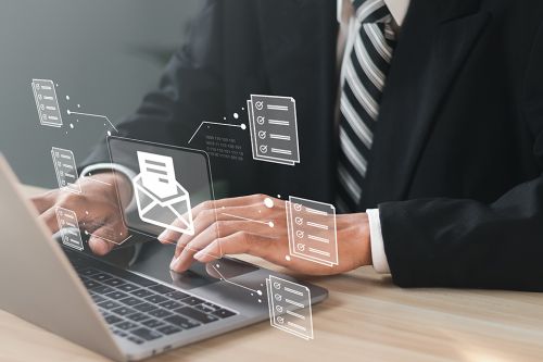 Mann vor Laptop mit schwebendem digitalen Brief über der Tastatur